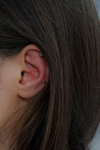 Faux Snug (dupla Conch) piercing kombináció és egy virágos köves Helix ékszer a fül felső peremén.