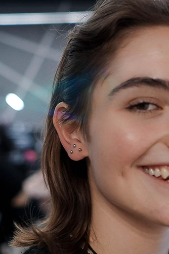 Stacked Lobe (halmozott fülcimpa) piercing: három apró golyós ékszer háromszög alakban elhelyezve.