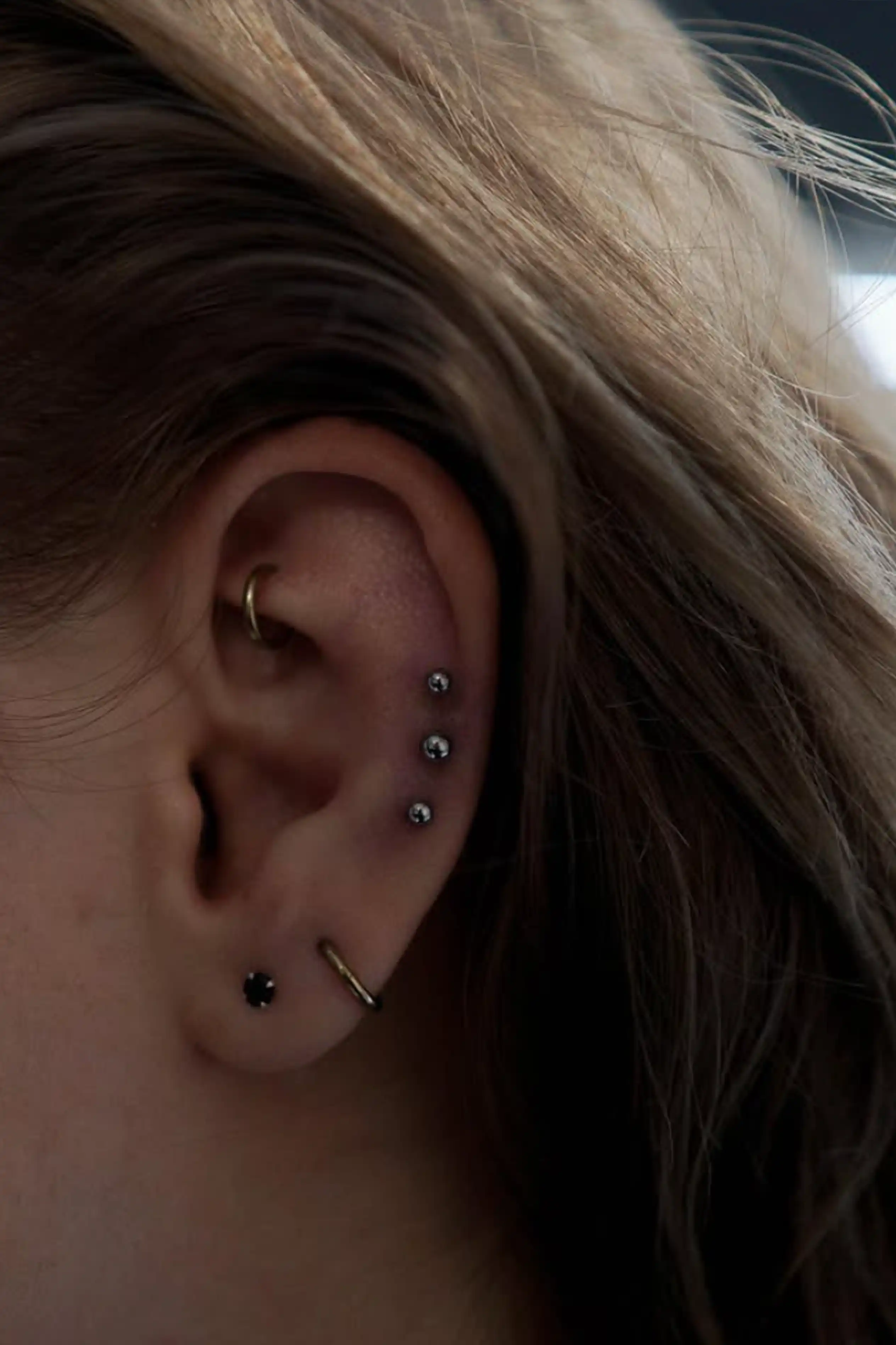 Triple Flat / Helix piercing: három egymás alatti porc ékszer precíz elrendezésben, Soospierce munkája.